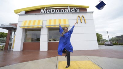 Archways to Opportunity alum throwing graduation cap into the air