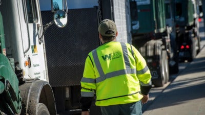 An employee walks toward a garbage collection truck in San Leandro, Calif., on Feb. 12, 2018.