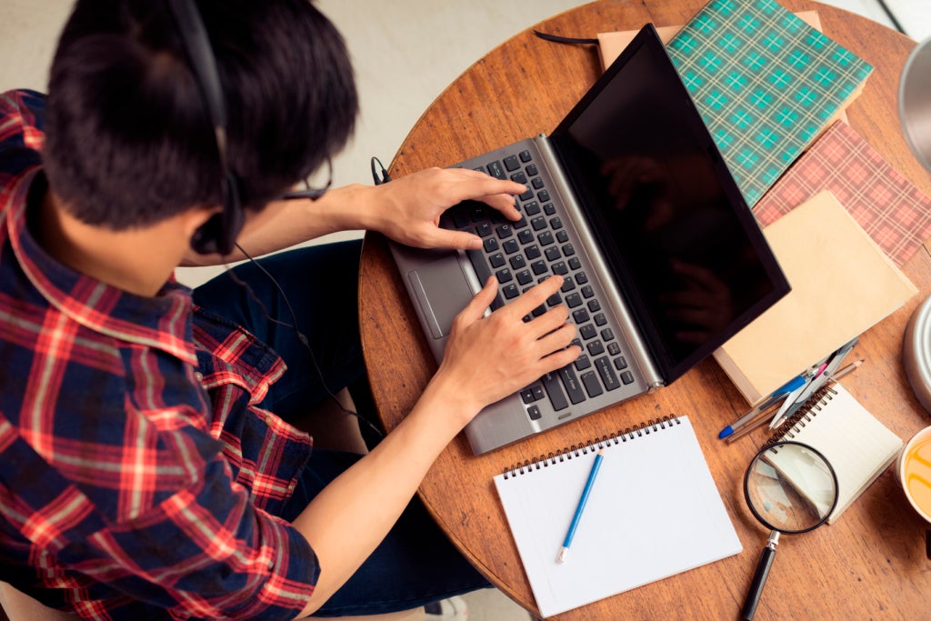 Young man in headphones working on laptop, view from above