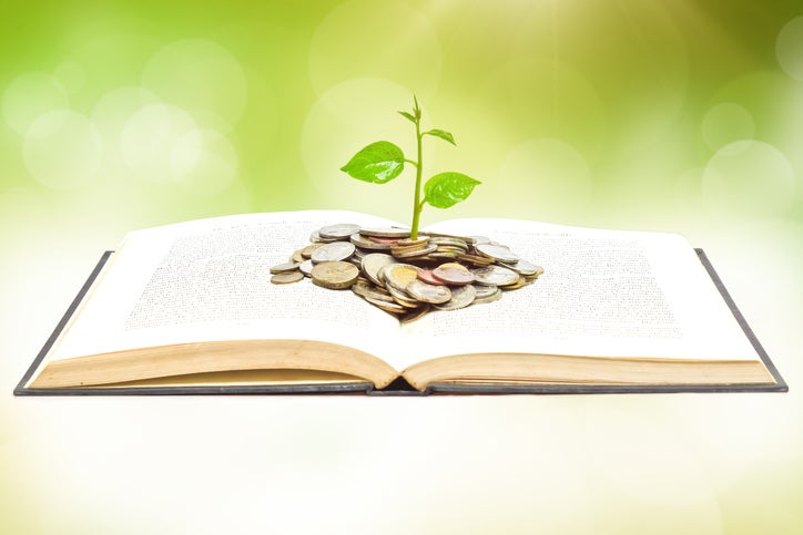 tree growing from book with coins