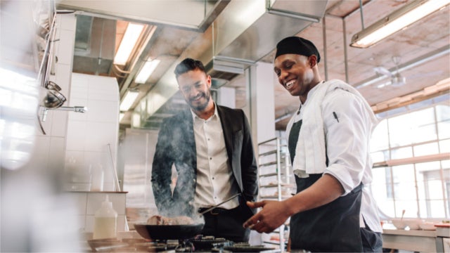 Chef and manager smiling in restaurant kitchen
