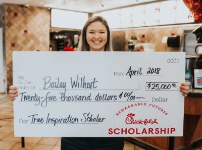 Chick-fil-A employee holding a giant scholarship check.