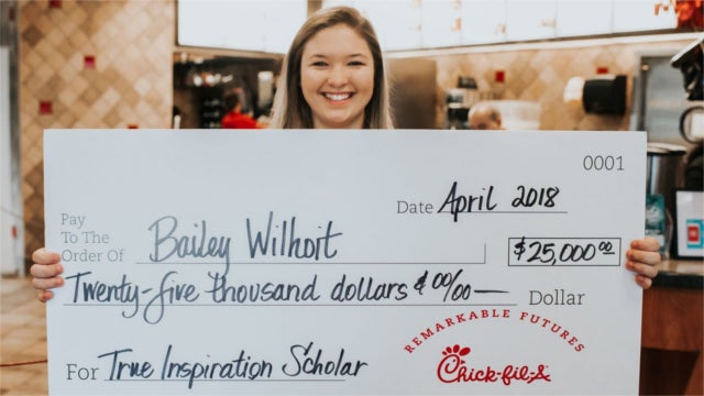 Chick-fil-A employee holding a giant scholarship check.
