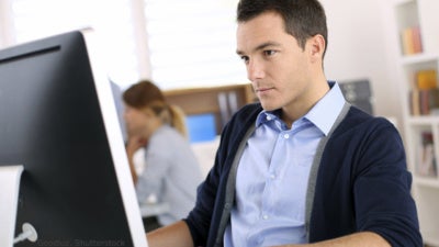 Adult male sitting in front of a computer monitor in an office