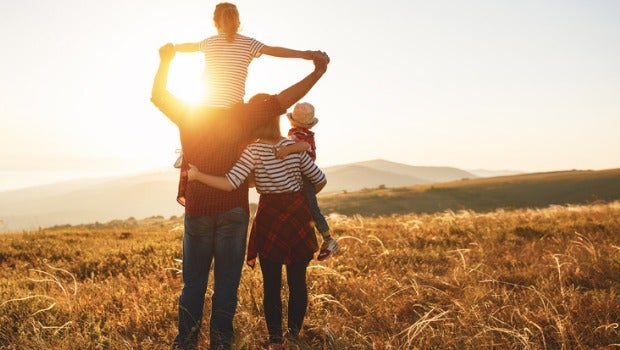 A family standing in a field at sunset.