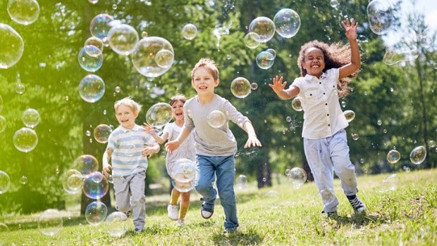 Children chasing bubbles in a park.