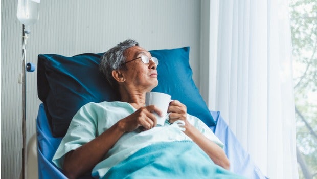A man sits in a hospital bed looking out the window.
