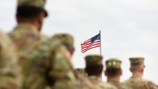 American soldiers with US flag in background.