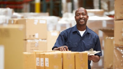 African American man working in warehouse, preparing goods for shipment