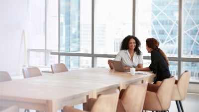 Two Businesswomen Using Laptop In Boardroom Meeting