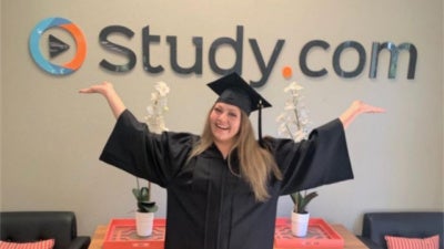 Working Scholar graduate celebrates in front of the Study.com logo