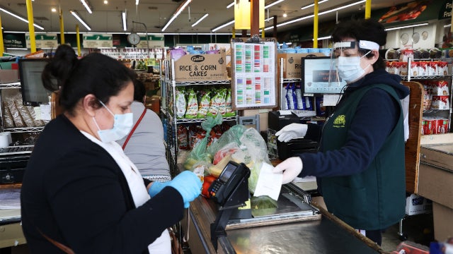 Grocery store worker and customer wearing masks in the checkout line (Photo courtesy of Marketplace. Credit: Al Bello/Getty Images)