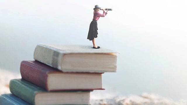 Miniature woman looks at the infinity with the spyglass on a scale of books