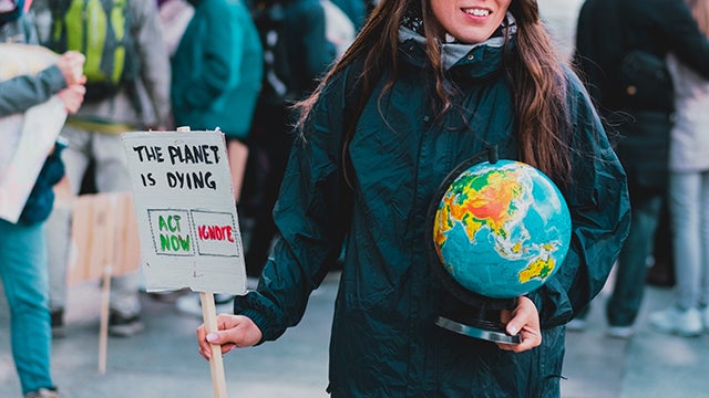 Woman holding globe and sign at climate protest