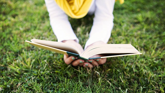 Person lying down in the grass reading