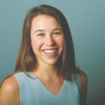 Alexandra Telleur's headshot. Image depicts a person with long hair behind their shoulders wearing a sleeveless top smiling at the camera.