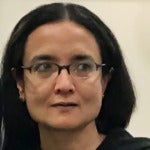 Deborani Duttagupta's headshot. Impact depicts a person with long hair wearing glasses looking away from the camera.