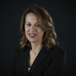 Mara Lucin's headshot. Image depicts a person with shoulder-length hair wearing a blouse and necklace smiling at the camera.