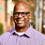 Zaid Zaid's headshot. Image depicts a person wearing glasses and a collared shirt outside on a street smiling at the camera.