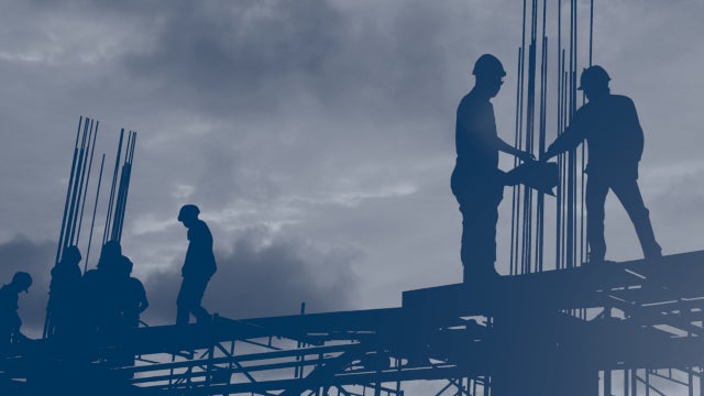 Silhouette image of construction workers standing on scaffolding