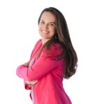 Woman smiles in bright pink blazer and long brown hair