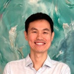 Headshot of man with dark black short hair on green background