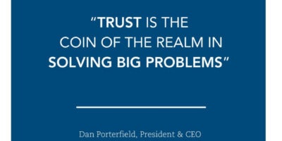 A dark blue graphic with white text that contains a quote from Aspen Institute Dan Porterfield on it. The quote reads "Trust is the coin of the realm in solving big problems."