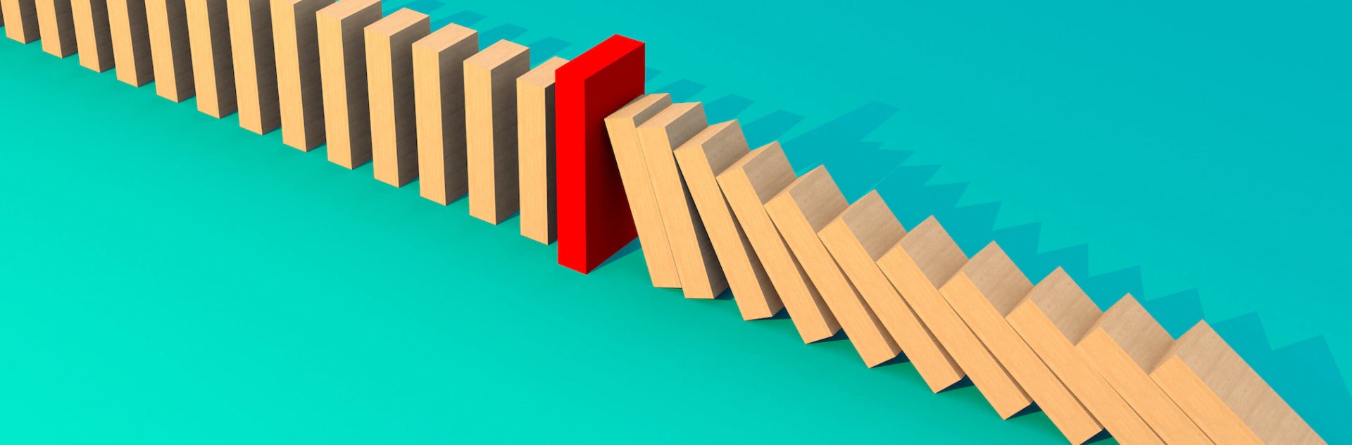 Wooden blocks falling in a domino effect. One red upright block in the middle stops the chain.