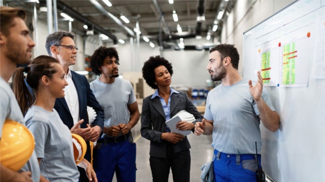 A factory worker presents a new business strategy to his managers and colleagues.