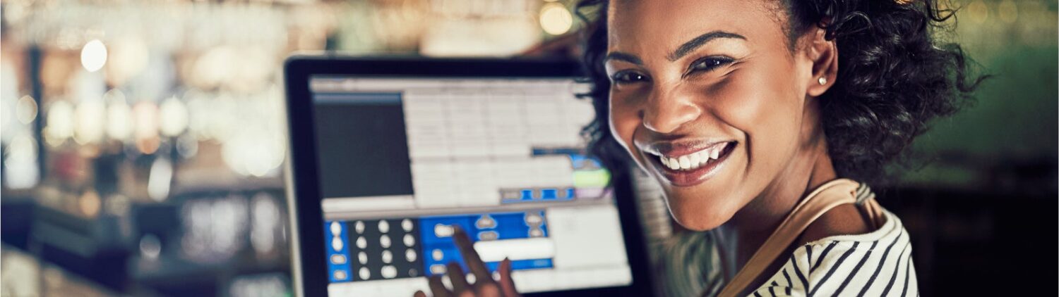 Photo of a smiling Black woman using a touchscreen cash register