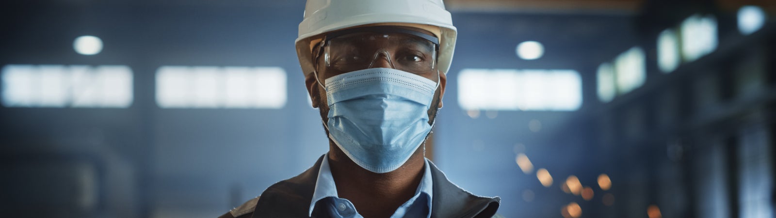 Photo of a steelworker wearing a hard hat, safety goggles, and face mask.