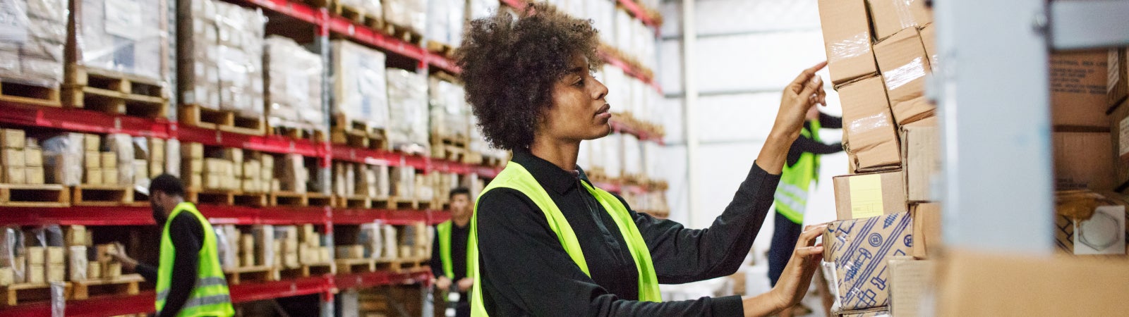 African American woman warehouse worker grabs boxes from a shelf