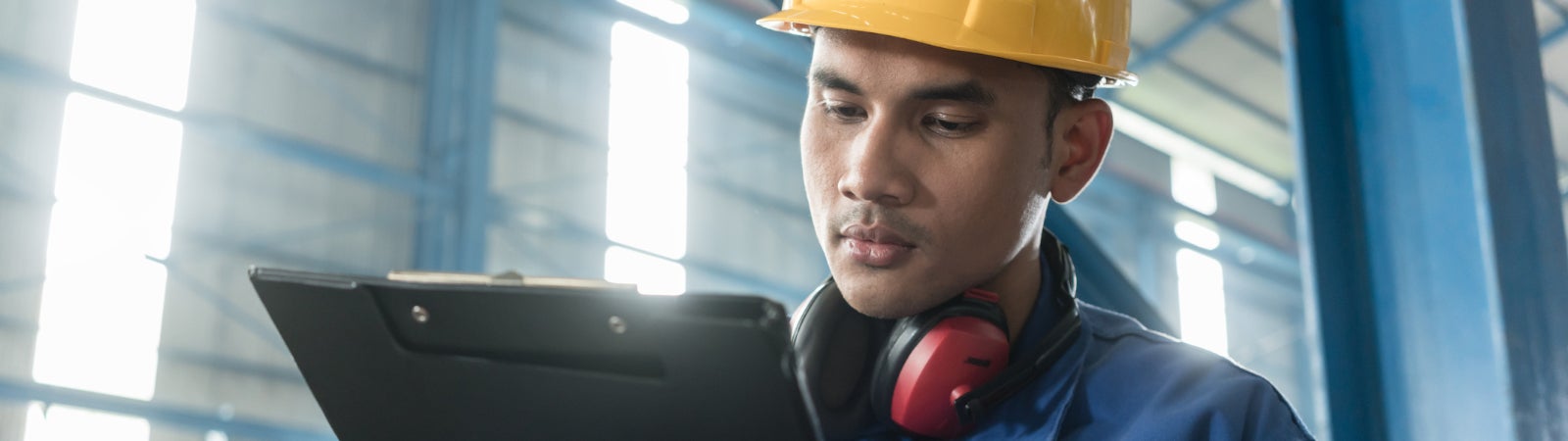 Photo of a manufacturing worker writing on a clipboard