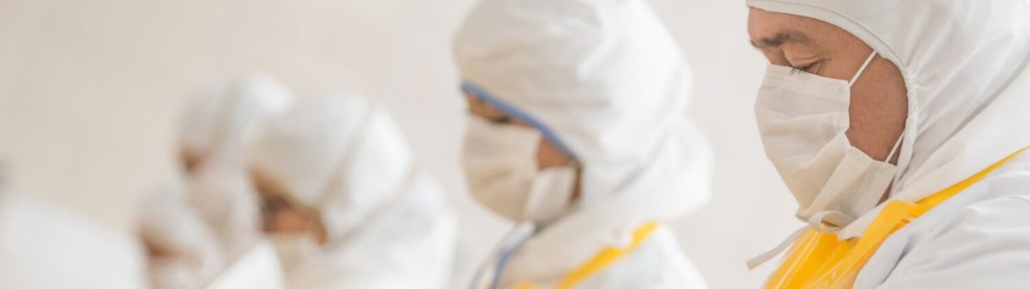 Workers at a poultry factory wearing protective clothing and masks