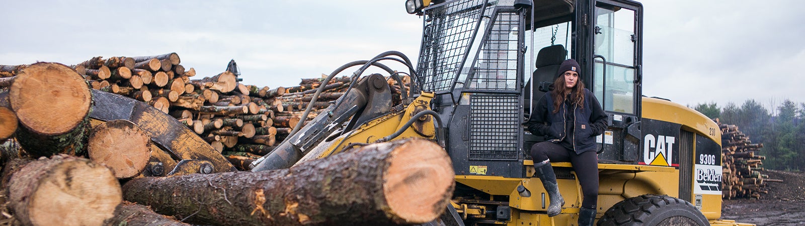 A Vermont worker sits on equipment by logs