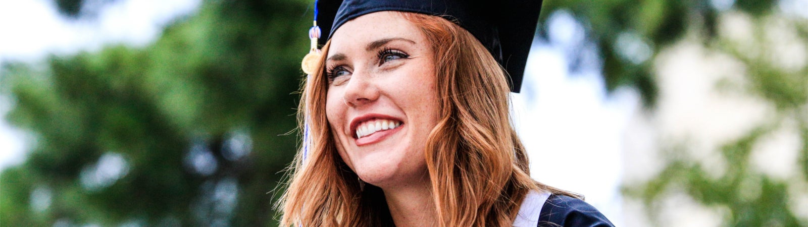 Smiling woman in graduation cap and gown. Photo by Chichi Onyekanne on Unsplash.