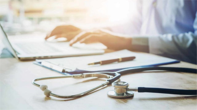 Doctor typing information on Laptop in Hospital office focus on Stethoscope