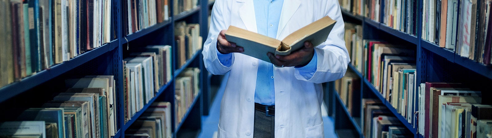 Doctor standing in library, studying information about corona virus.