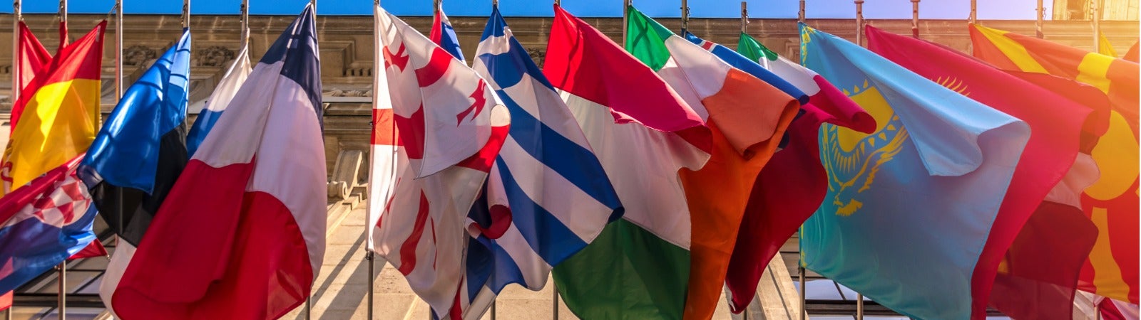 Flags from many different countries hanging from the side of a building.