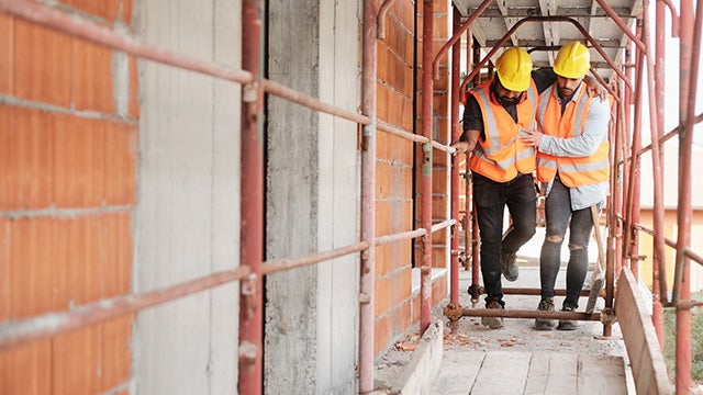 Injured construction worker being helped by colleague