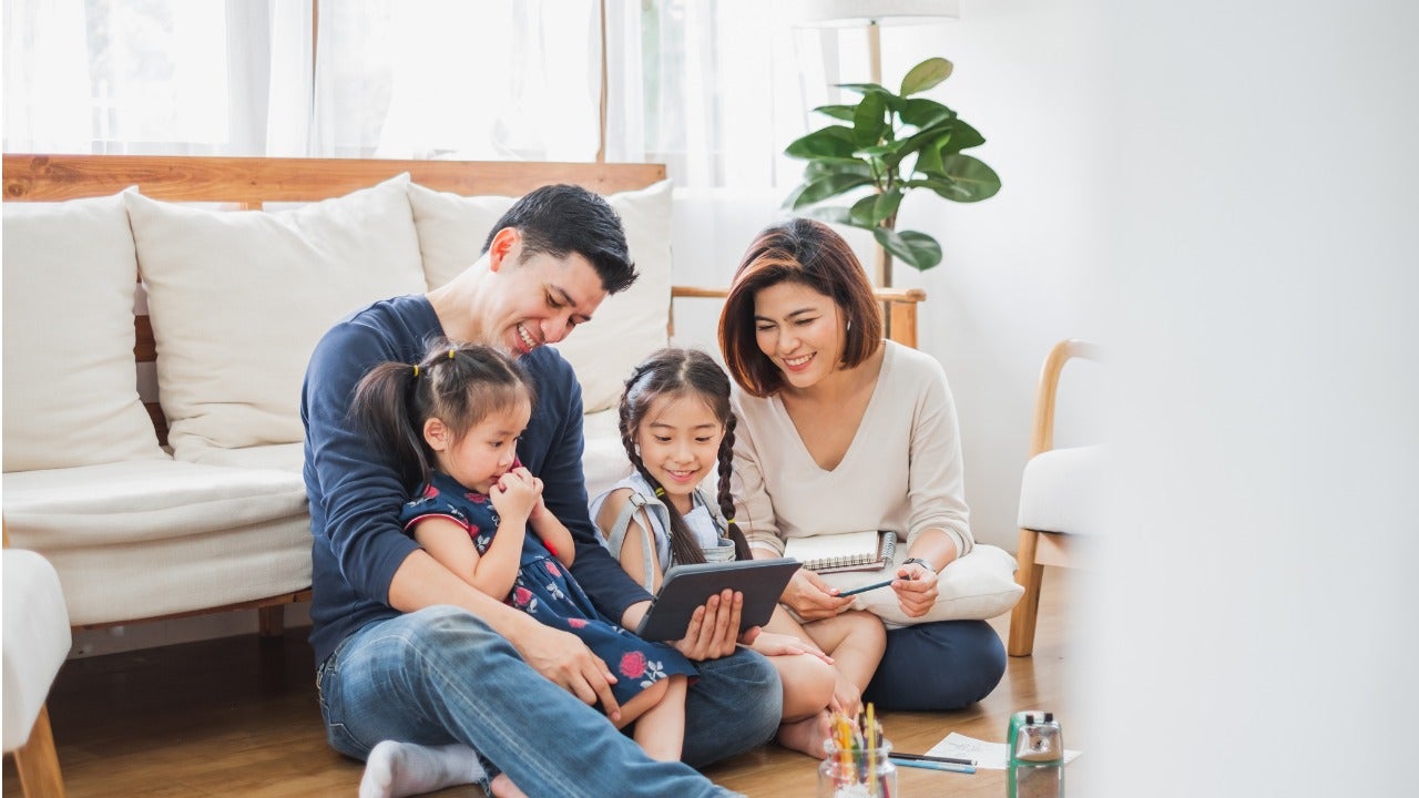 A family with two children sitting using a tablet together.