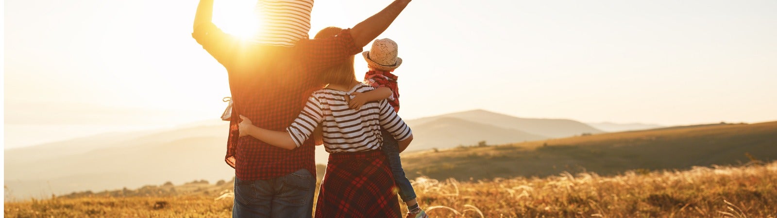 A family standing in a field at sunset.