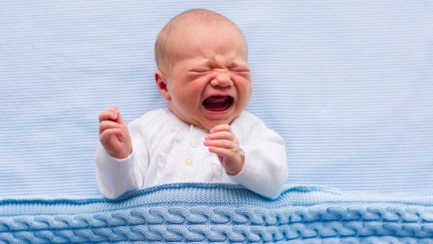 A baby crying on a hospital blanket.