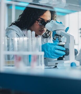 Scientist in lab looking at microscope