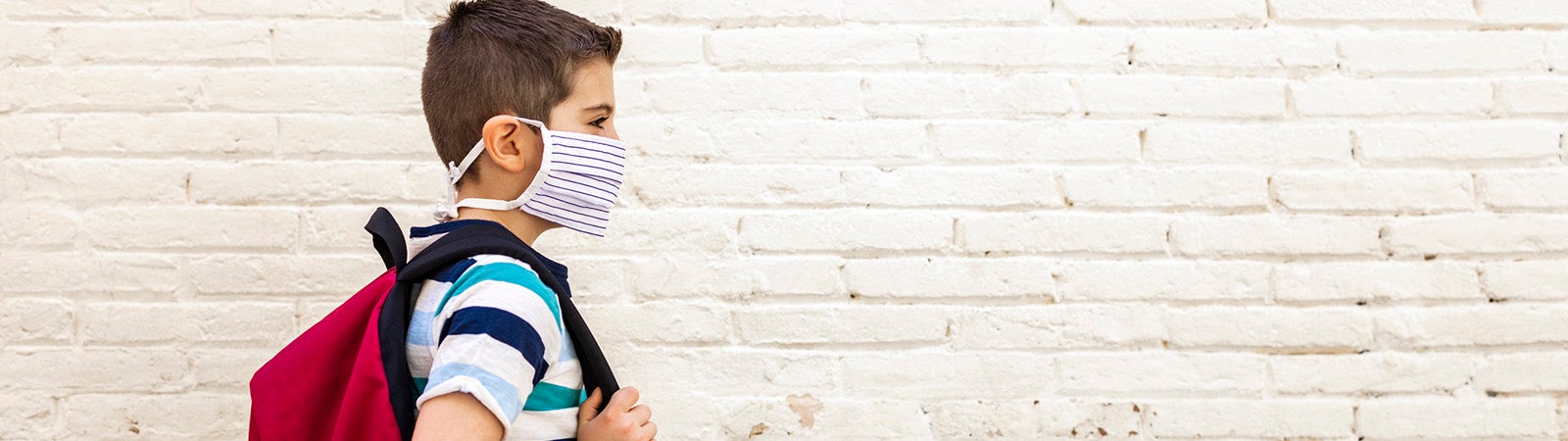 Boy in mask walking to school