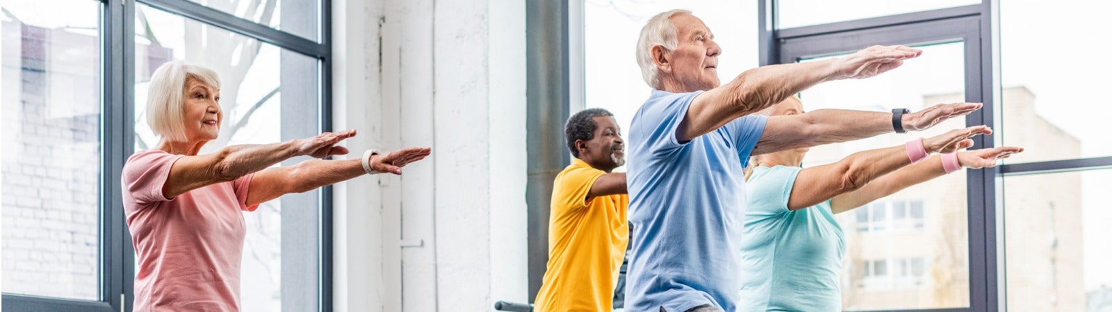 A group of seniors exercising on step platforms in a gym.