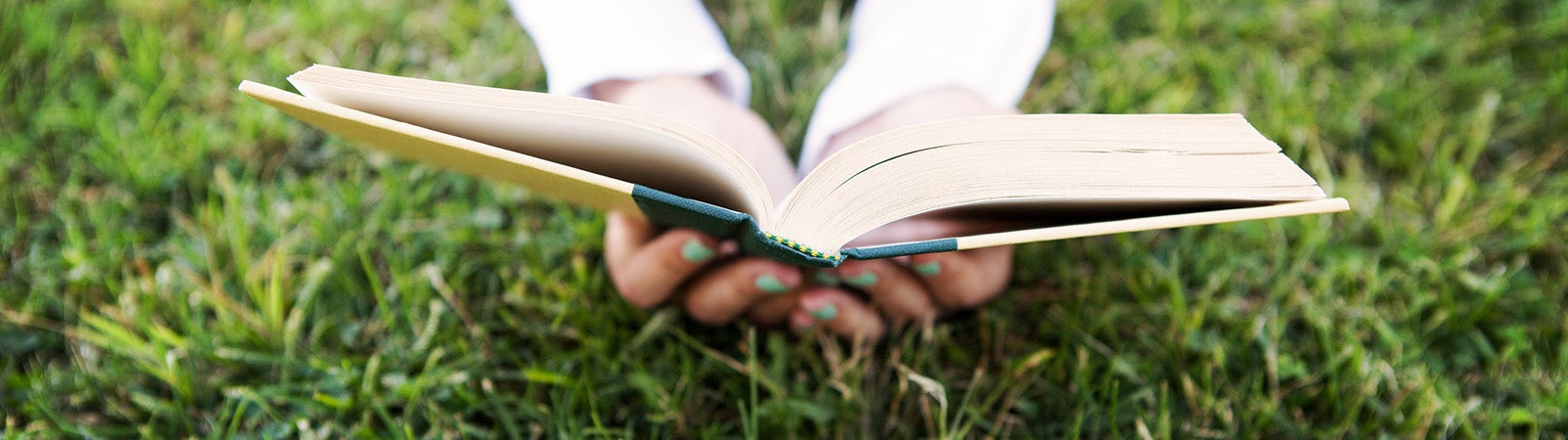Person lying down in the grass reading