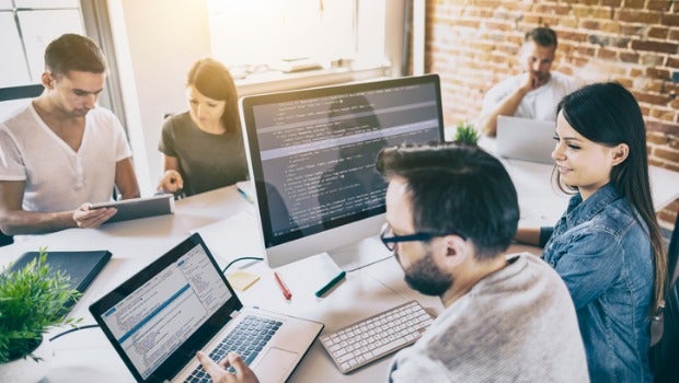People sitting around computers looking at lines of code.