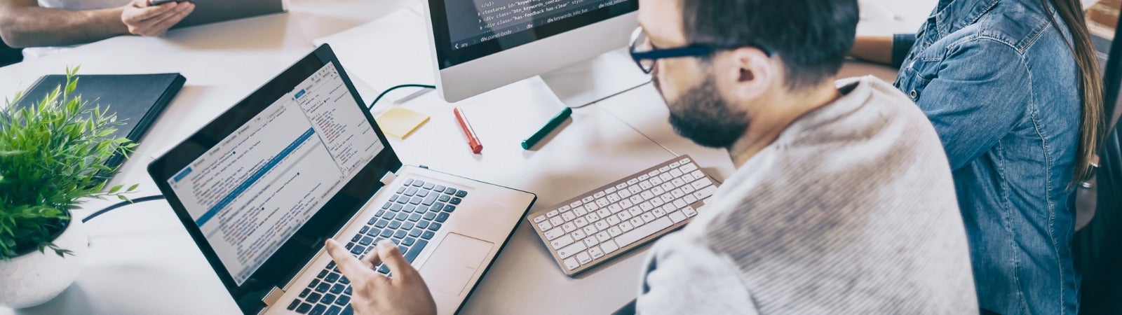 People sitting around computers looking at lines of code.