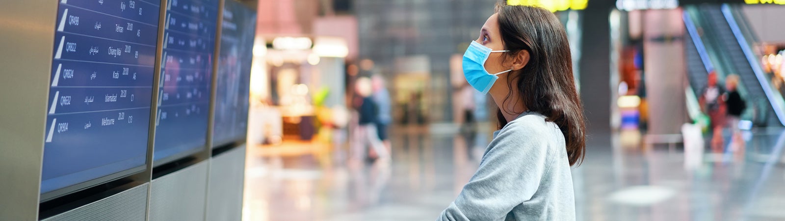 Woman with mask looking at departure board